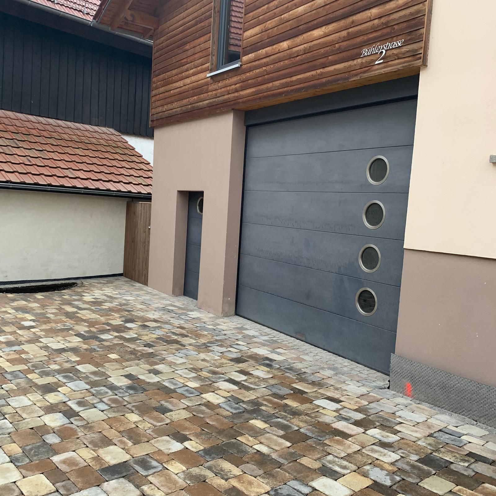 Verlegung von Pflaster und Schachtabdeckung mit Natursteinen integriert.